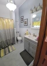 bathroom featuring wainscoting, toilet, vanity, and a shower with shower curtain