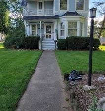 victorian-style house featuring a front yard and a balcony