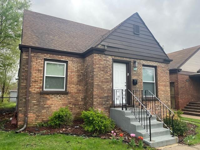view of front of home featuring brick siding, roof with shingles, and fence