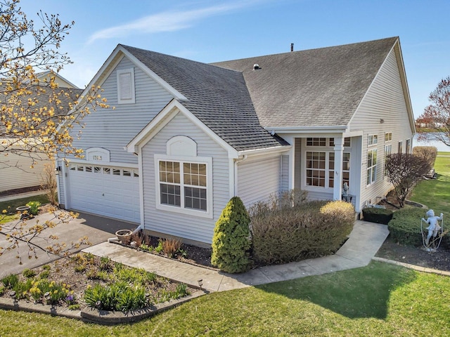 view of front facade with a garage, roof with shingles, driveway, and a front yard