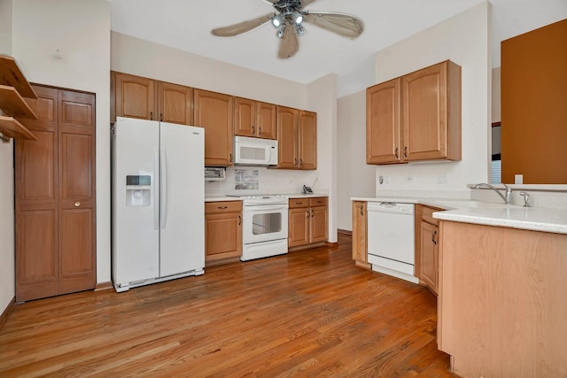 kitchen with white appliances, a sink, a ceiling fan, wood finished floors, and light countertops