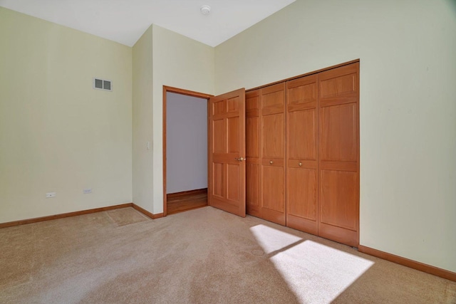 unfurnished bedroom featuring light carpet, baseboards, and a closet