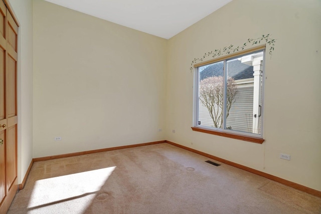 spare room with light carpet and baseboards