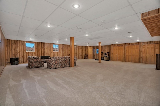 below grade area featuring carpet, wood walls, and a drop ceiling