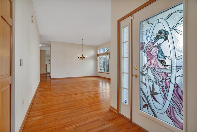 entryway with a chandelier, light wood-style floors, and baseboards