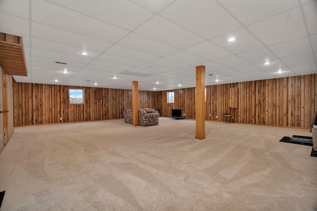 basement with carpet floors, wood walls, and a drop ceiling