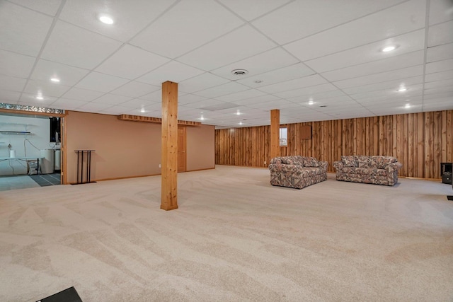 unfurnished living room featuring carpet floors, wooden walls, recessed lighting, a paneled ceiling, and baseboards
