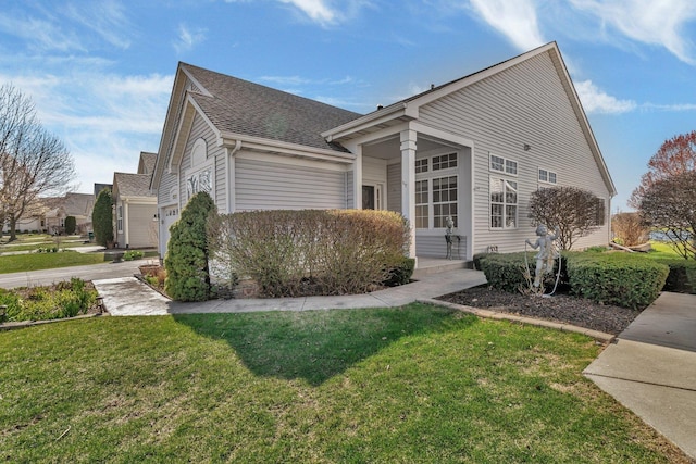 view of side of home with a lawn, a shingled roof, and driveway