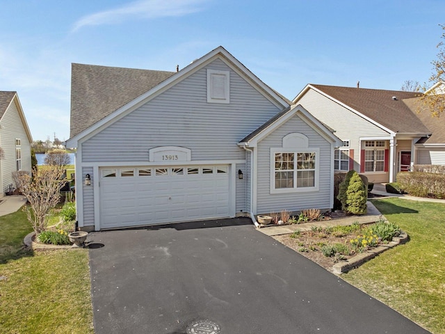 traditional home with asphalt driveway, an attached garage, roof with shingles, and a front lawn