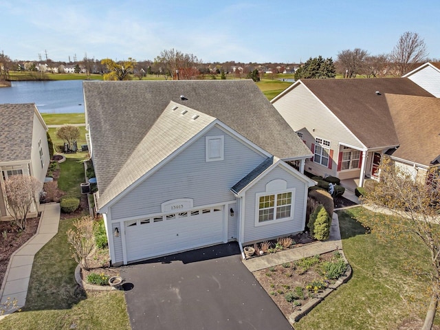 traditional-style home with roof with shingles, asphalt driveway, a water view, and a front lawn