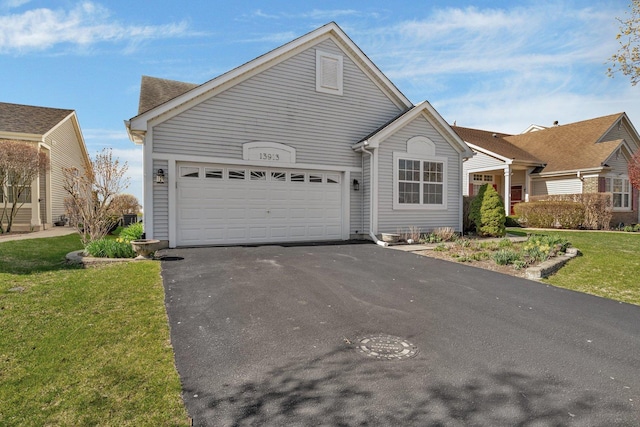 view of front of home featuring driveway, an attached garage, and a front lawn