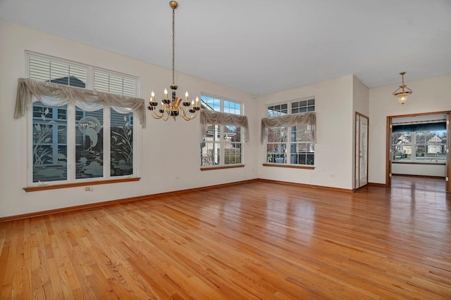 unfurnished dining area with light wood-style floors, a chandelier, healthy amount of natural light, and baseboards