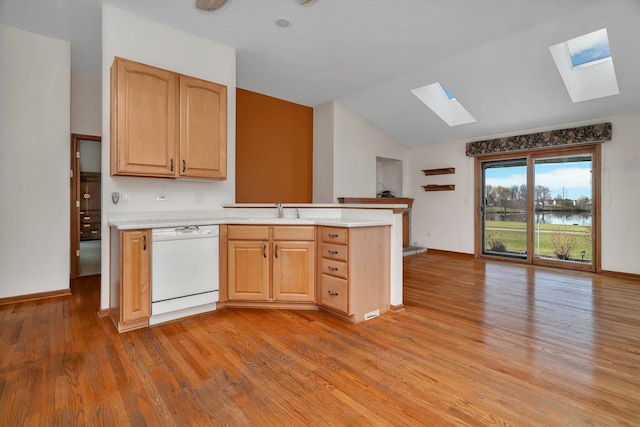 kitchen with dishwasher, a skylight, a sink, light wood finished floors, and a peninsula