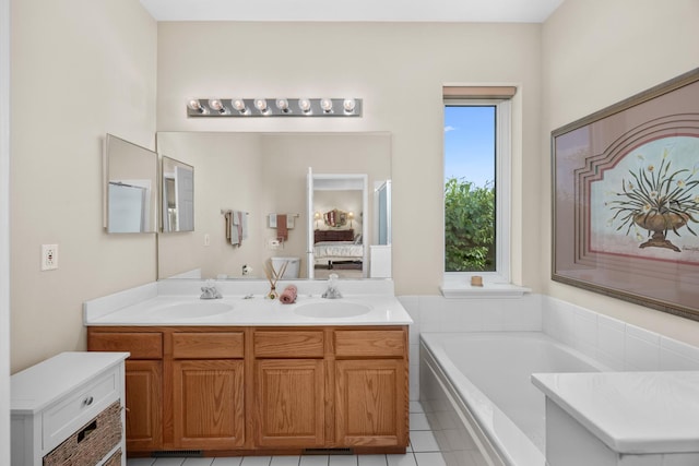 ensuite bathroom featuring tile patterned flooring, double vanity, and a bath
