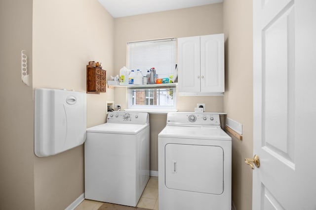 clothes washing area with washer and clothes dryer, cabinet space, baseboards, and light tile patterned floors