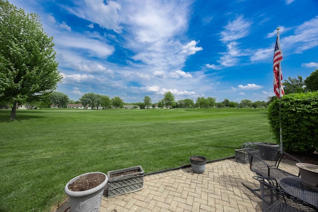 view of grassy yard featuring a patio area and view of golf course
