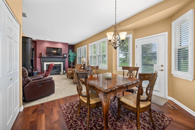 dining space featuring a chandelier, a fireplace with flush hearth, dark wood-style flooring, baseboards, and recessed lighting