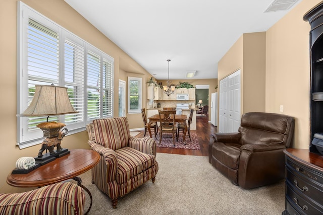 living room with a chandelier, carpet flooring, and wood finished floors