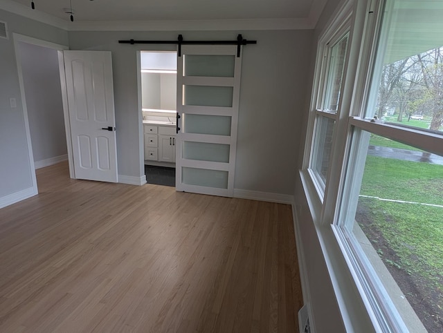 27W075 Fleming Dr, Winfield, IL 60190 - unfurnished bedroom with a barn door, wood finished floors, baseboards, connected bathroom, and ornamental molding