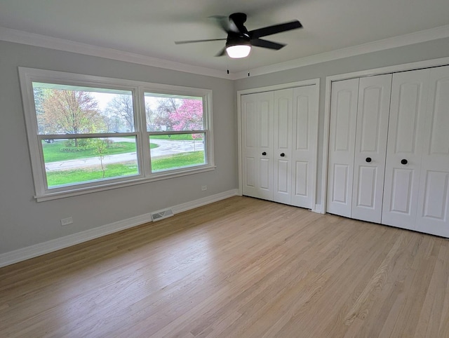 27W075 Fleming Dr, Winfield, IL 60190 - unfurnished bedroom featuring light wood-style floors, two closets, ornamental molding, baseboards, and a ceiling fan