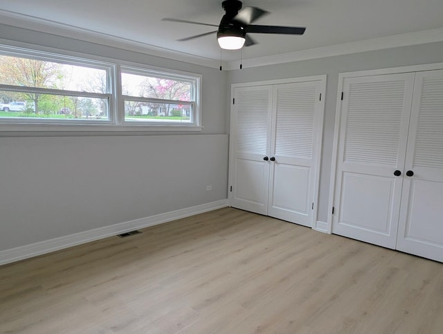 27W075 Fleming Dr, Winfield, IL 60190 - unfurnished bedroom featuring multiple closets, light wood finished floors, crown molding, baseboards, and ceiling fan