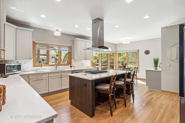 551 Salceda Ln, Mundelein, IL 60060 - kitchen featuring island exhaust hood, backsplash, appliances with stainless steel finishes, light countertops, and a breakfast bar area