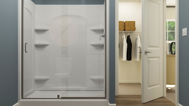 bathroom featuring wood finished floors and a shower stall