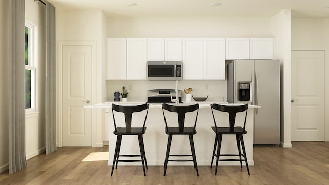 kitchen featuring stainless steel appliances, a kitchen island, white cabinets, and light wood-style floors