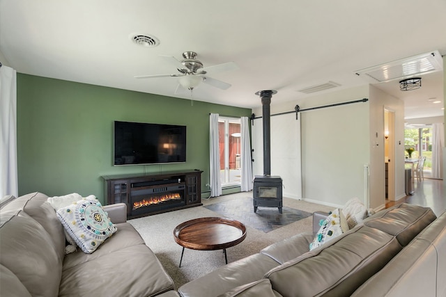 543 Blackhawk Dr, Lake In The Hills, IL 60156 - carpeted living area with a ceiling fan, a wood stove, a baseboard heating unit, a glass covered fireplace, and baseboards