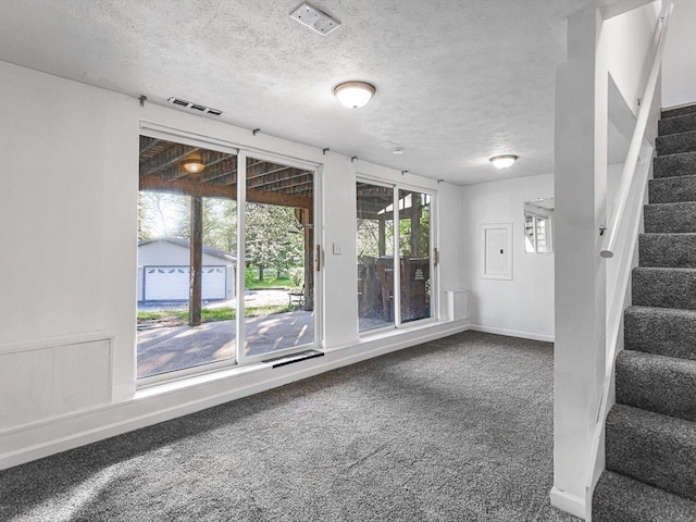 1659 Larchmont Rd, Davis, IL 61019 - empty room featuring dark colored carpet, stairway, a textured ceiling, and baseboards
