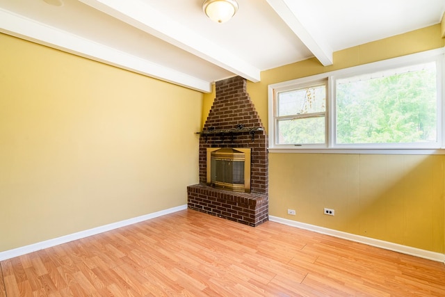 unfurnished living room with wood finished floors, beamed ceiling, baseboards, and a fireplace