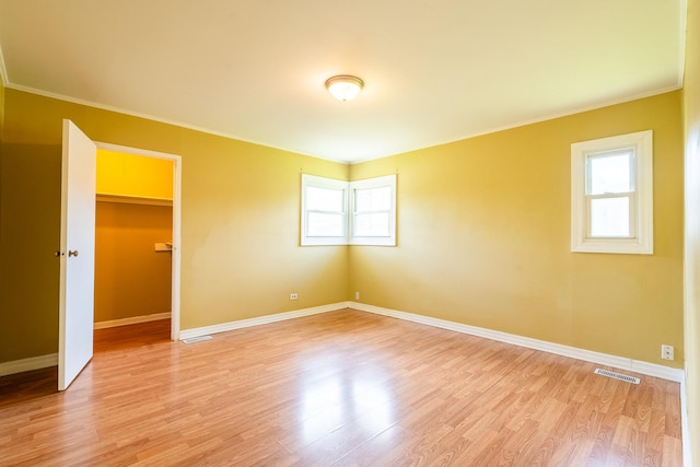 unfurnished room featuring ornamental molding, baseboards, and light wood-style floors