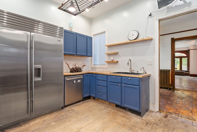 3230 W Fulton Blvd, Chicago, IL 60624 - kitchen featuring appliances with stainless steel finishes, blue cabinets, a sink, open shelves, and butcher block countertops