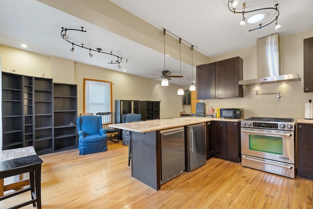 3230 W Fulton Blvd, Chicago, IL 60624 - kitchen with stainless steel gas range oven, wall chimney exhaust hood, refrigerator, dark brown cabinets, and track lighting
