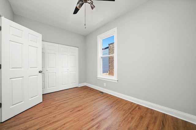 unfurnished bedroom featuring baseboards, light wood-style flooring, a closet, and ceiling fan