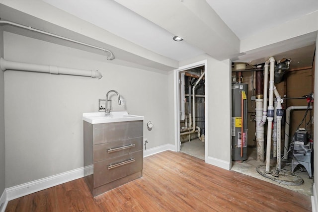 finished basement with water heater, baseboards, light wood finished floors, and a sink