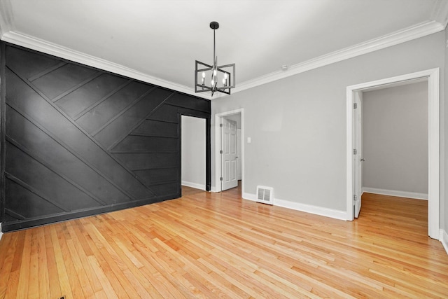 spare room with crown molding, a chandelier, light wood finished floors, and baseboards