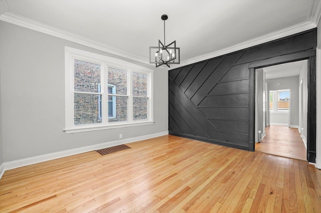 unfurnished dining area with light wood-type flooring, baseboards, a chandelier, and ornamental molding