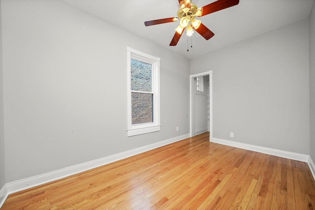 spare room with baseboards, light wood-style flooring, and a ceiling fan