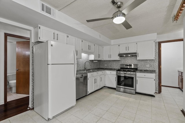 kitchen with appliances with stainless steel finishes, under cabinet range hood, a sink, ceiling fan, and white cabinetry