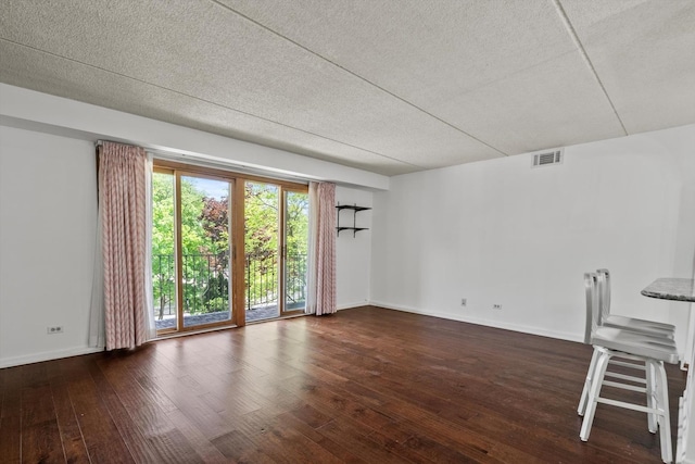 empty room featuring a textured ceiling, baseboards, and wood-type flooring