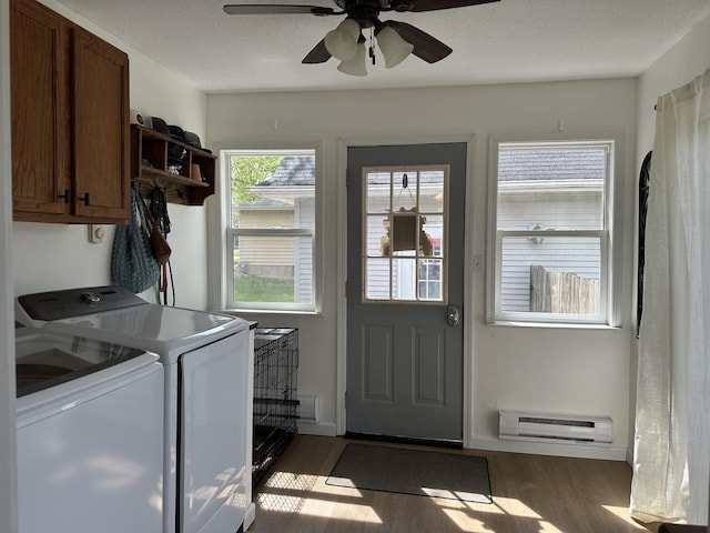 laundry room featuring separate washer and dryer, a baseboard radiator, cabinet space, wood finished floors, and ceiling fan