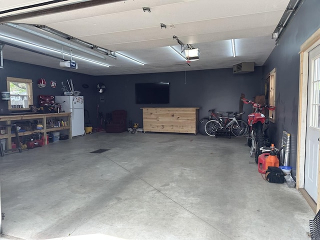 garage with freestanding refrigerator, a garage door opener, and a workshop area
