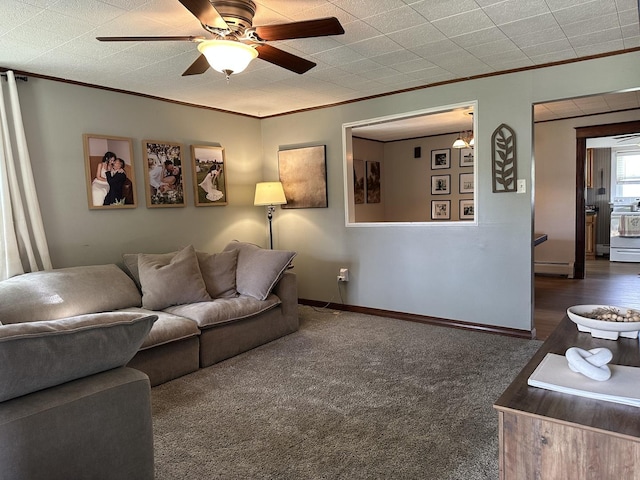 carpeted living room featuring ornamental molding, a ceiling fan, baseboard heating, and baseboards