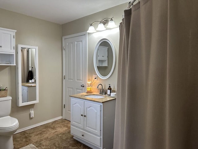 bathroom featuring toilet, vanity, and baseboards