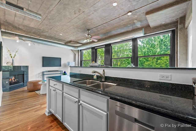 1001 W 15th St Unit 243, Chicago, IL 60608 - kitchen featuring stainless steel dishwasher, a sink, a tile fireplace, ceiling fan, and light wood-style floors