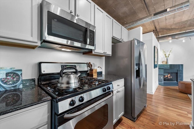1001 W 15th St Unit 243, Chicago, IL 60608 - kitchen with stainless steel appliances, light wood finished floors, dark stone counters, a fireplace, and white cabinets