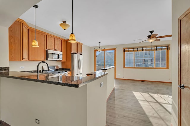 15810 Scotsglen Rd, Orland Park, IL 60462 - kitchen featuring appliances with stainless steel finishes, ceiling fan, light wood-style flooring, a peninsula, and dark stone countertops