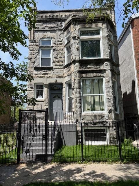 3320 W Monroe St, Chicago, IL 60624 - view of front of house featuring stone siding, a fenced front yard, and a gate