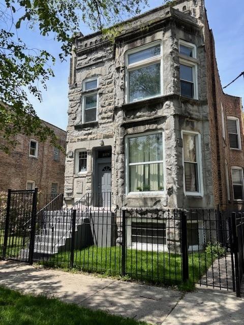 3320 W Monroe St, Chicago, IL 60624 - view of front of house featuring stone siding, a fenced front yard, and a gate